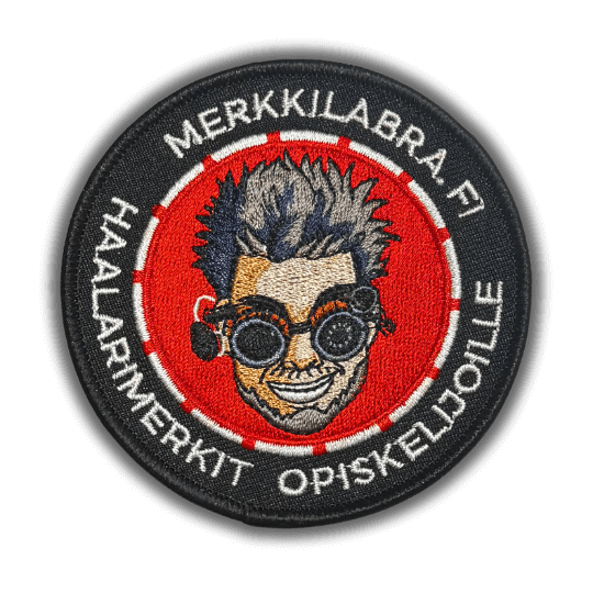 Merkkilabran logo brodeerattu haalarimerkki saumatulla reunalla, tekstillä: ''Merkkilabra.fi haalarimerkit opiskelijoille''