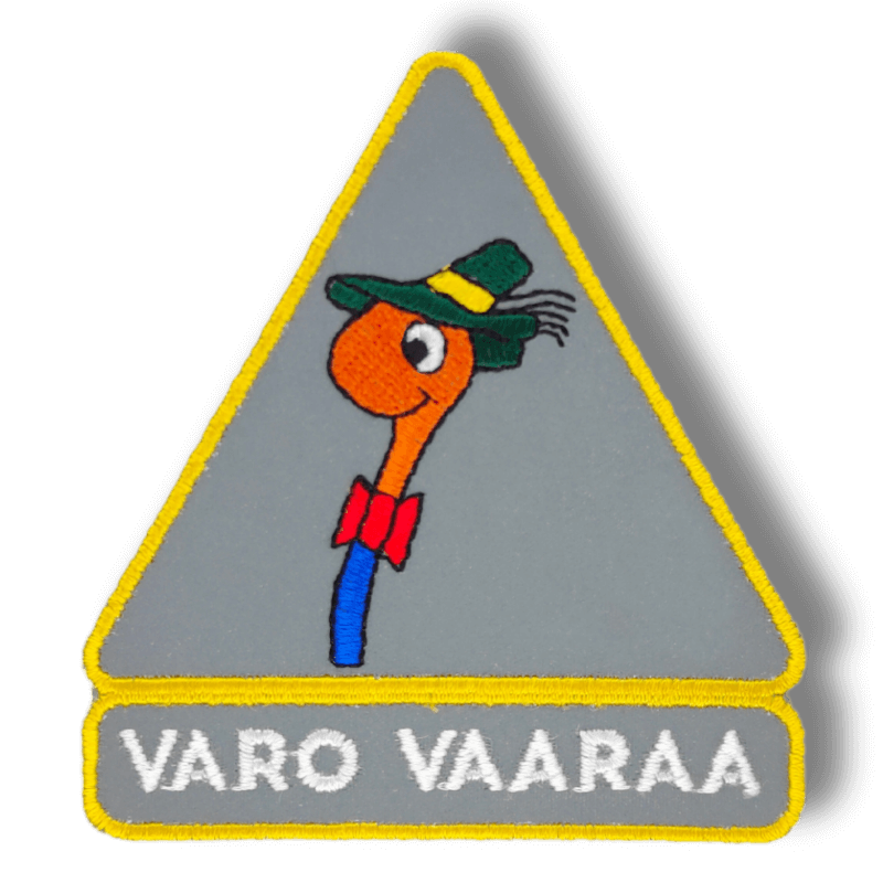 Brodeerattu haalarimerkki Varo vaaraa -meemistä laserleikatulla reunalla ja heijastavalla taustakankaalla, tekstillä: ''Varo vaaraa''
