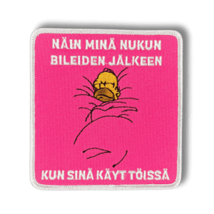 Brodeerattu haalarimerkki Homer Simpsonista nukkumassa saumatulla reunalla ja tekstillä: ''Näin minä nukun bileiden jälkeen, kun sinä käyt töissä''