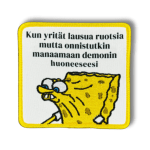 Brodeerattu ja printattu haalarimerkki Paavo Pesusienestä saumatulla reunalla ja tekstillä: ''Kun yrität lausua ruotsia, mutta onnistutkin manaamaan demonin huoneeseesi''