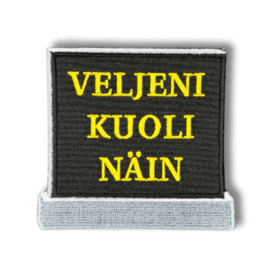 Brodeerattu haalarimerkki hautakivestä laserleikatulla reunalla ja tekstillä: ''Veljeni kuoli näin''