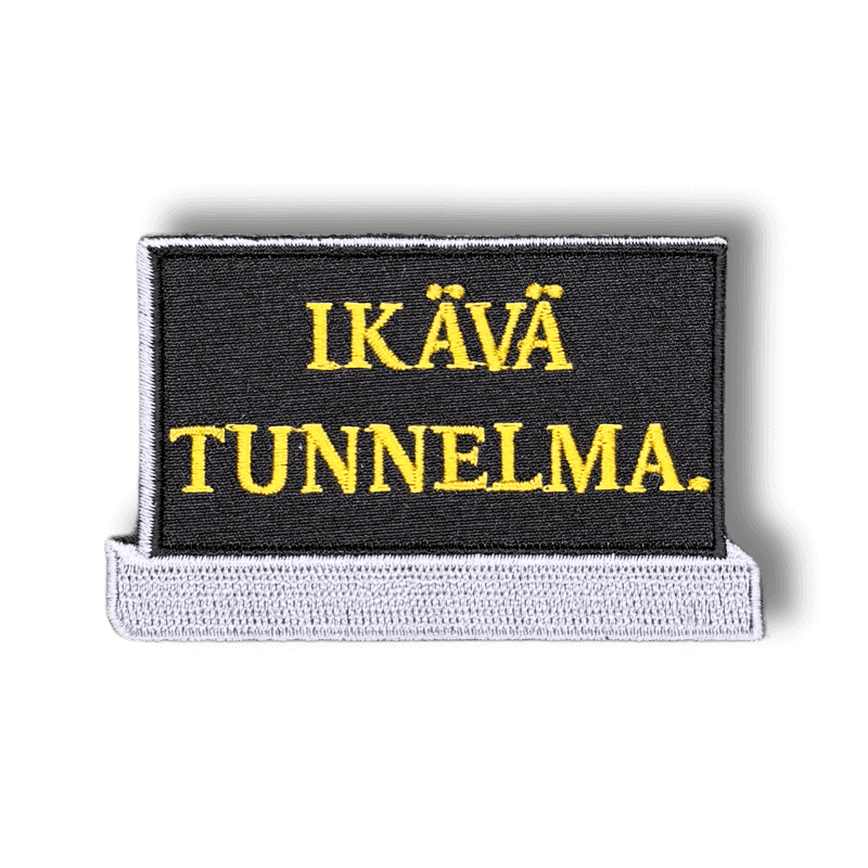 Brodeerattu haalarimerkki hautakivestä laserleikatulla reunalla ja tekstillä: ''Ikävä tunnelma.''