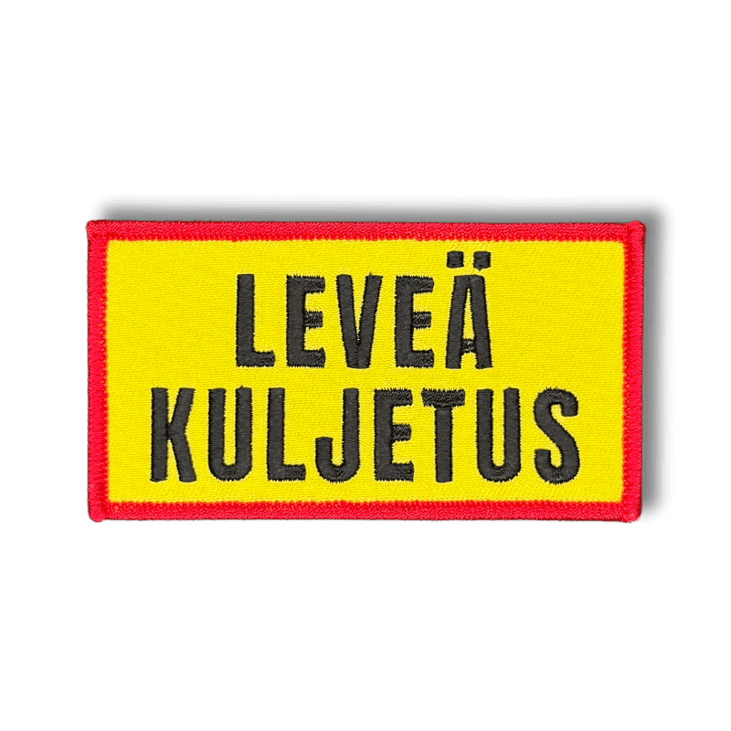 Brodeerattu haalarimerkki varoituskyltistä saumatulla reunalla ja tekstillä: ''Leveä kuljetus''
